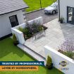 Outdoor patio area featuring light grey paving slabs installed with Joint-It Simple paving jointing compound. The landscaped space includes a metal bench, flowerbeds with purple and green plants, and decorative pots beside a white rendered house. Text overlay reads “Trusted by professionals. Loved by homeowners.” along with the Joint-It Simple branding in the bottom corner