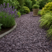Garden path made with 40mm crushed plum slate, bordered by lavender and ornamental grasses, with a rustic planter and lush greenery in the background