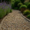 Curved garden path laid with 20mm Dorset flint gravel in natural grey, buff, and amber tones, bordered by lavender and ornamental plants in soft daylight