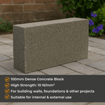 Rectangular 100mm dense concrete block placed on a paved patio surface in a landscaped garden, with a brick wall and flowering shrubs in the background. Ideal for structural and loadbearing construction