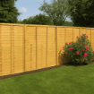 A 6ft TAFS lap fence panel installed in a garden setting with neatly trimmed grass, flowering plants, and shrubs, providing privacy and a natural timber aesthetic